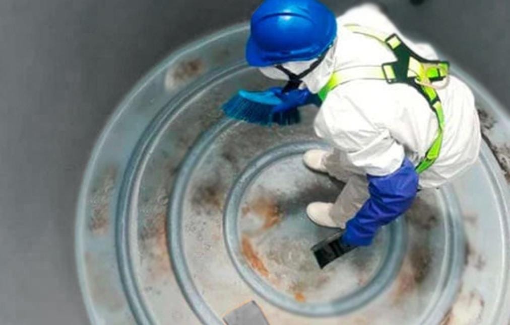 Técnico realizando lavado y cepillado profundo en base de tanque de agua